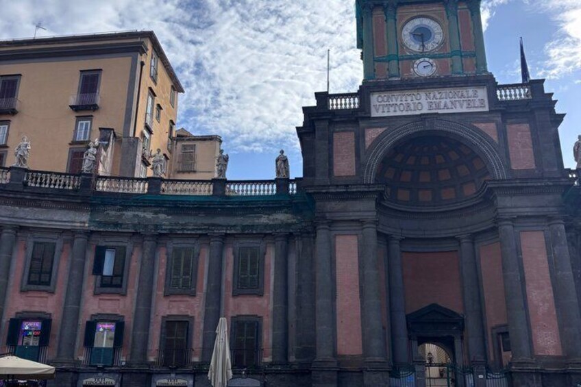 A historic building with a clock tower and a sign reading 'CONVITTO NAZIONALE VITTORIO EMANUELE.' 5