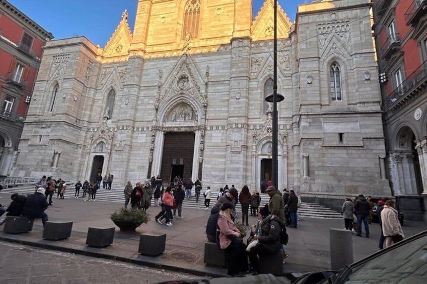 A historic cathedral with ornate architecture and a golden roof, surrounded by a crowd of people. 1
