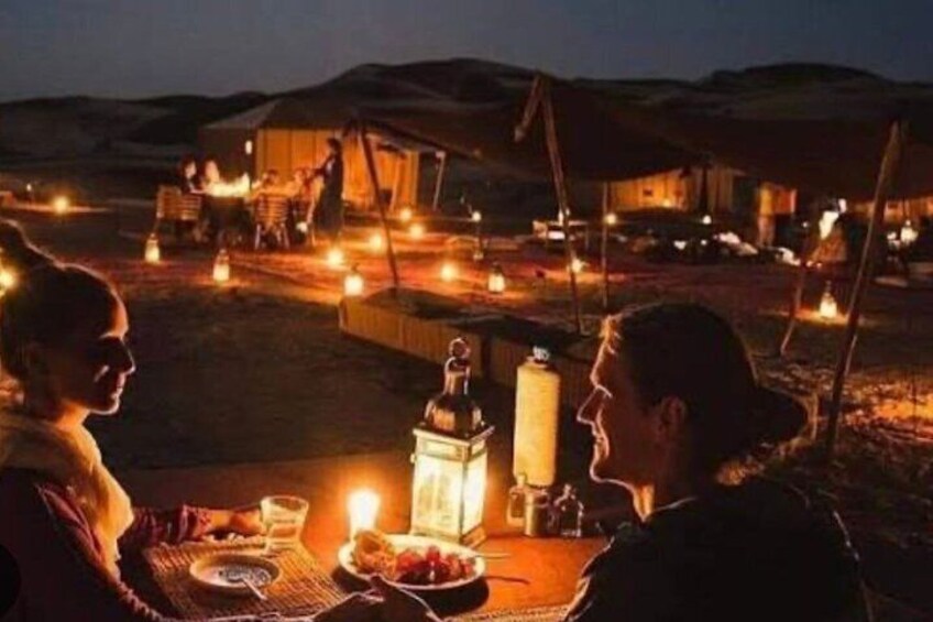 A desert camp with tents and a table set for a meal. 5