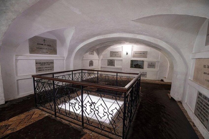 An underground room with arched ceilings, a central display case, and informational plaques. 2