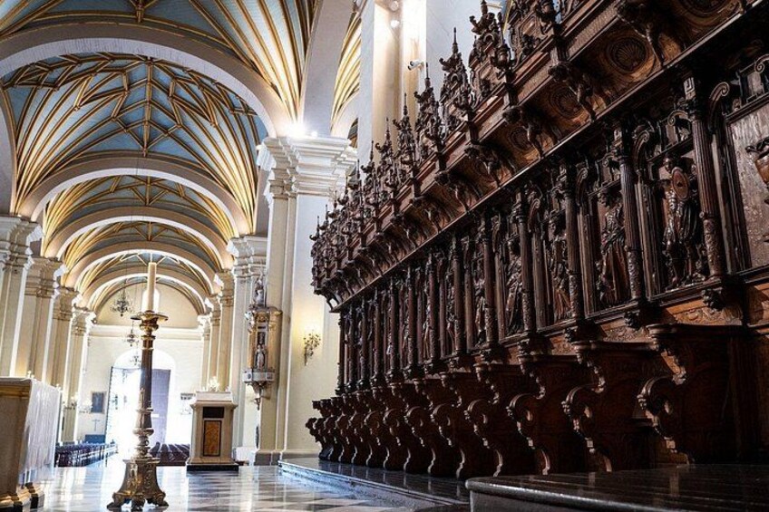 Interno di una chiesa decorata, con soffitti a volta alti, una lunga bancata con intagli elaborati e una navata centrale che conduce all'altare. 2