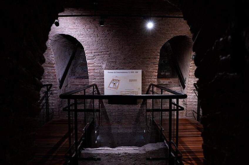 Una stanza sotterranea con pareti in mattoni, una ringhiera metallica e un poster appeso al muro. 4