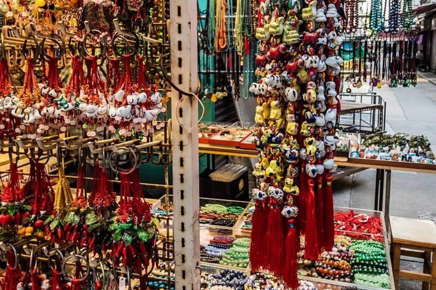 Ein Markt mit verschiedenen Ständen, an denen bunte Waren wie Spielzeug und Perlen verkauft werden. 3
