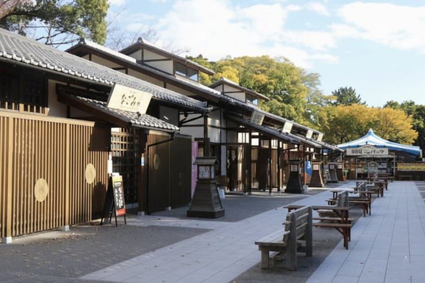 A traditional Japanese wooden building with a signboard, outdoor seating, and a blue tent. 2