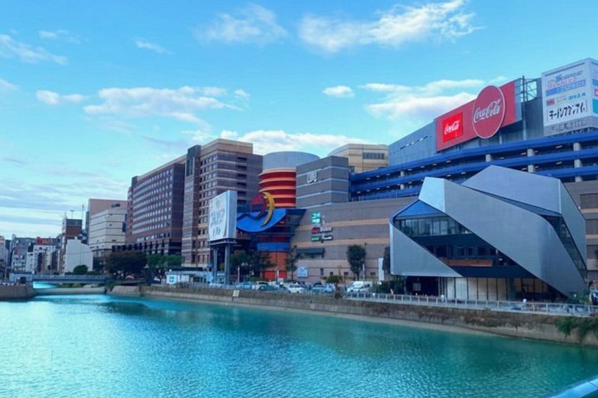 Eine Stadtlandschaft mit Fluss, moderner Architektur und einem Coca-Cola-Schild. 2