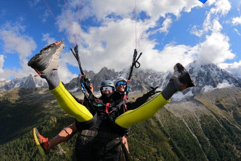 Two paragliders with their legs outstretched against a mountainous backdrop. 2
