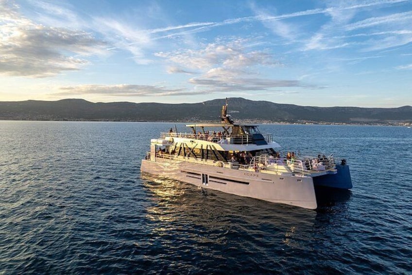 Un grand bateau sur une étendue d’eau calme, avec un paysage montagneux en arrière-plan. 1