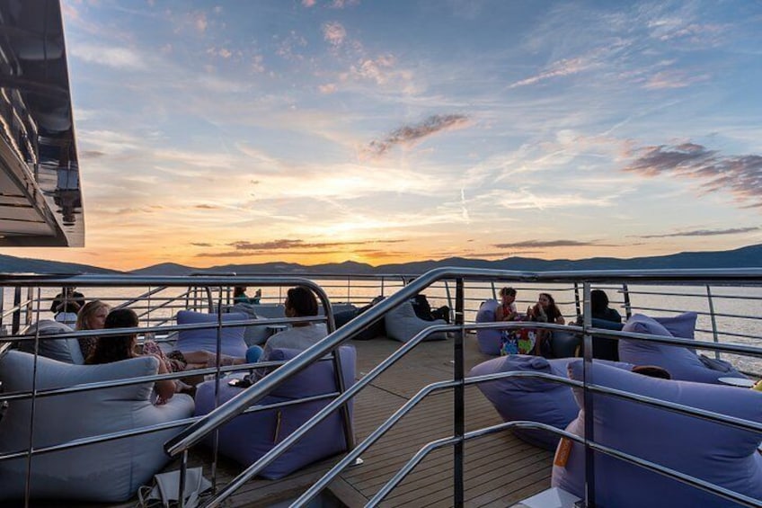 Un coucher de soleil sur le pont d’un bateau, avec des personnes se relaxant sur des fauteuils en forme de sac. 5