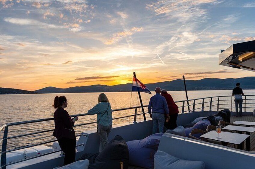 Un coucher de soleil sur une étendue d’eau, avec des personnes à bord d’un bateau. 3