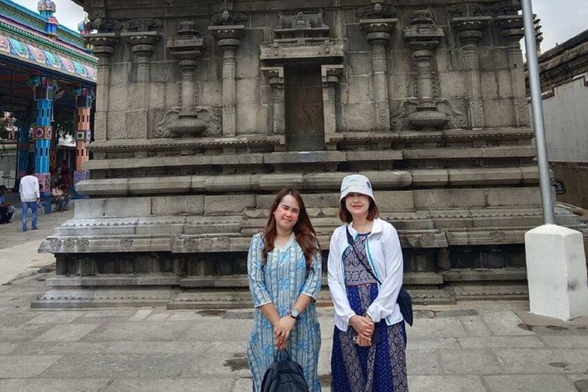 Two people standing in front of a stone temple with intricate carvings. 3