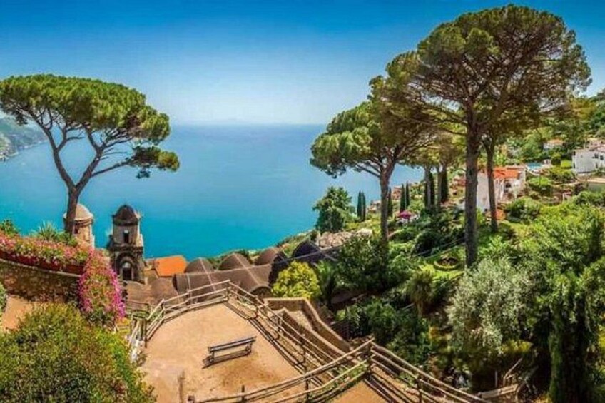 A coastal landscape with a clear view of the sea, a large tree, and a small building. 4