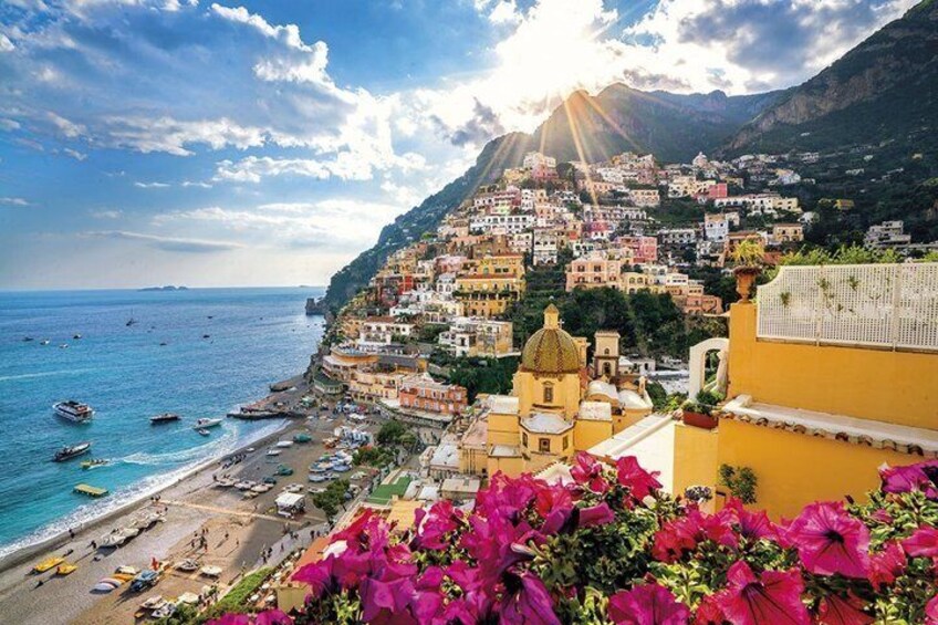 Un borgo costiero con edifici colorati, imbarcazioni sull'acqua e montagne sullo sfondo. 1