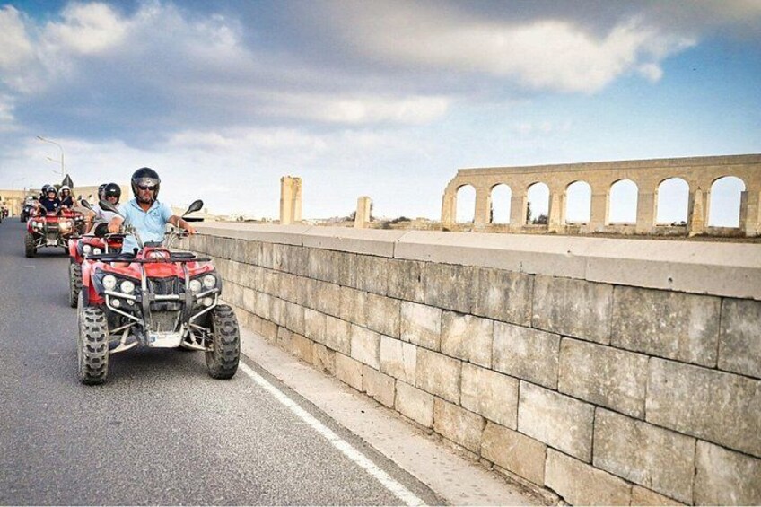 Un puente con arcos de piedra y un camino con vehículos todo terreno. 2