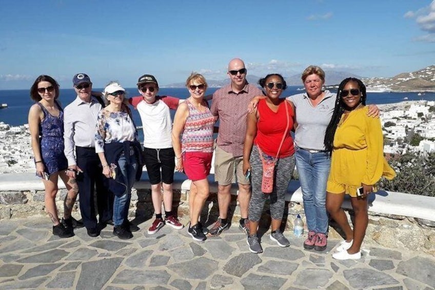 En grupp människor som står på en stenlagd gång med ett kustlandskap i bakgrunden. 2
