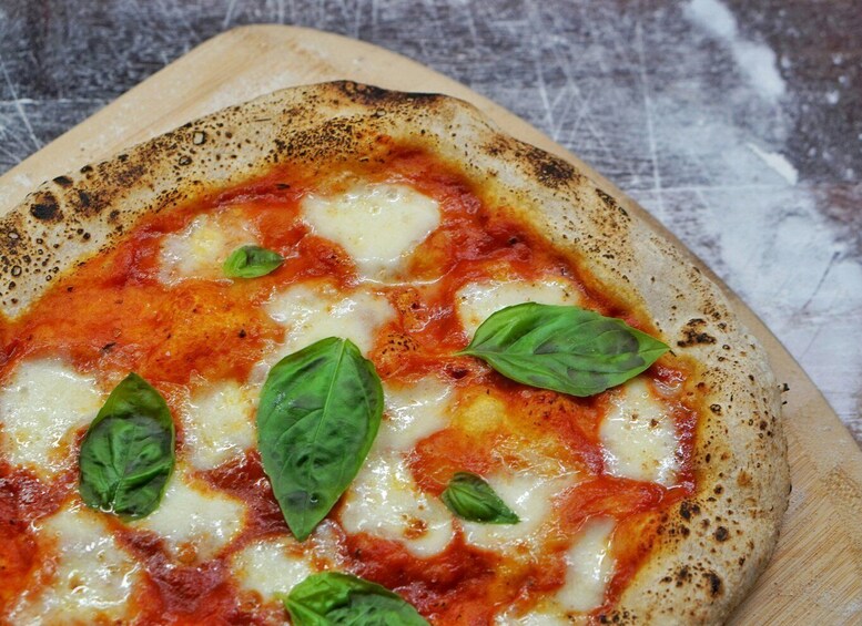 A pizza with cheese and basil leaves on a wooden board. 1