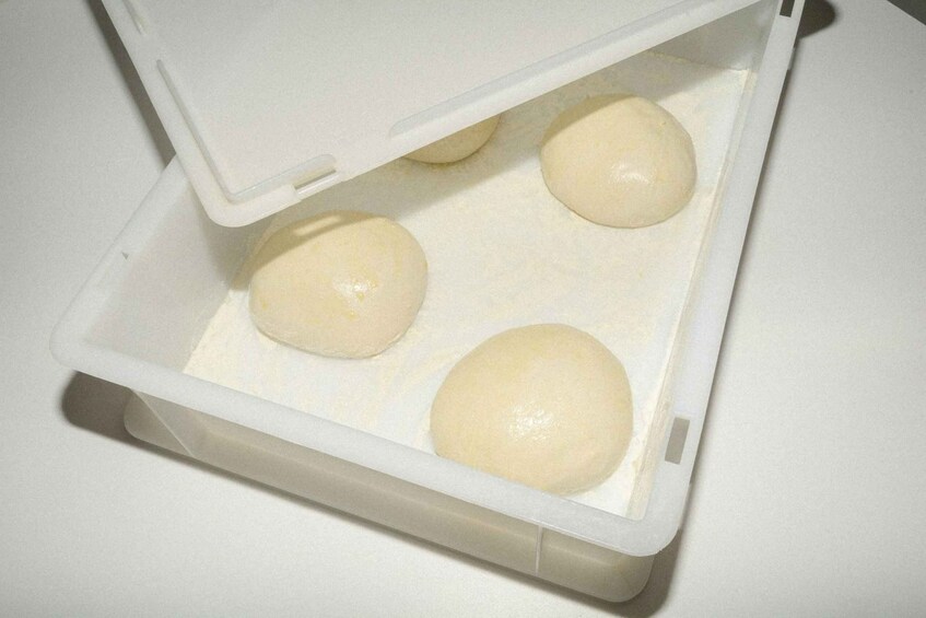 A plastic container with four dough balls. 4