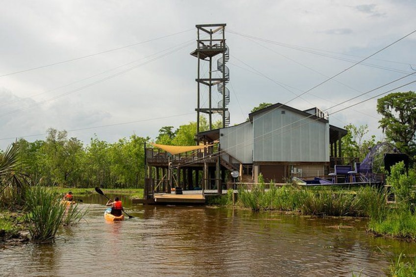 A waterway with a kayak, a wooden dock, and a large industrial building. 3