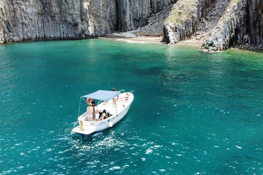 Een boot op turquoise water, omgeven door rotsachtige kliffen. 1