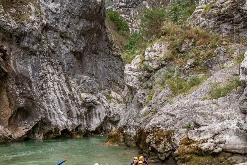 Ein felsiger Canyon mit einem Fluss, einem Kajak und zwei Personen im Wasser. 4