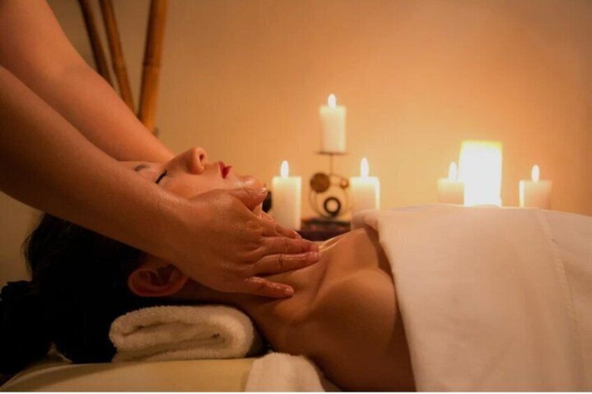 A person receiving a massage with candles in the background. 1