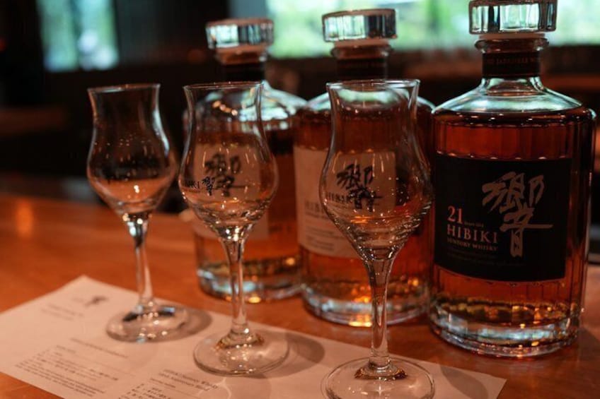 A bottle of Hibiki whiskey, two glasses, and a menu on a wooden table. 5