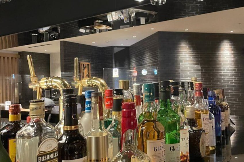 A bar with various liquor bottles and a gold faucet. 2