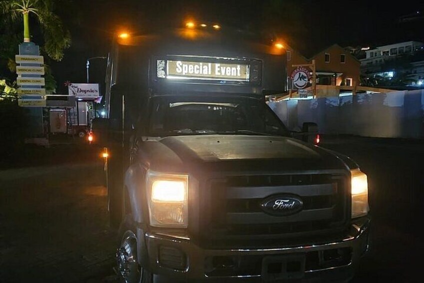 Een Ford vrachtwagen met een bord met de tekst 'Special Event' erop, geparkeerd in de nacht met de koplampen aan. 2