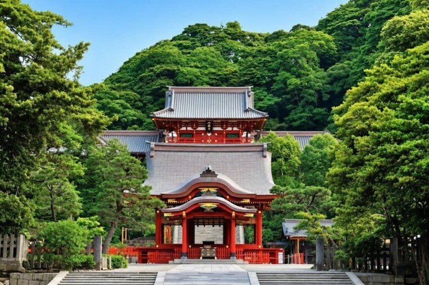 Ein traditioneller japanischer Tempel mit mehrstufigem Dach, umgeben von üppigem Grün. 2
