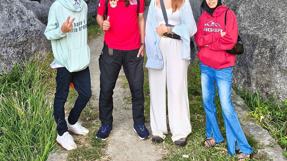 Four people standing on a path with grass and rocks around them. 2