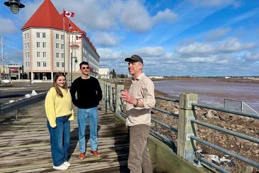 A wooden boardwalk with a building in the background, a river, and a cloudy sky. 5