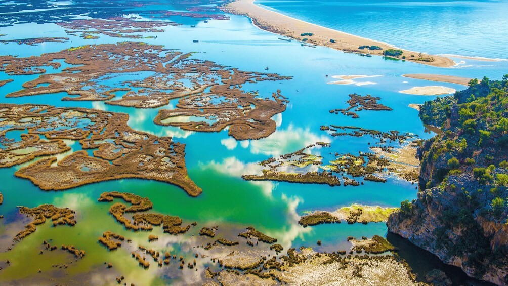 An aerial view of a coastal area with mangrove forests, clear blue waters, and a sandy beach. 1