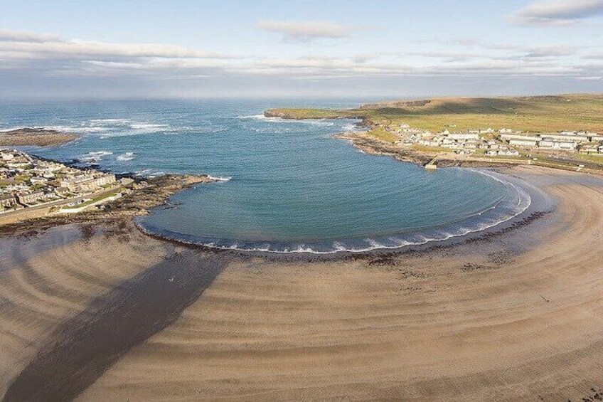 Un paysage côtier caractérisé par une baie en forme de courbe, une plage de sable et un petit village situé près de l’eau. 2