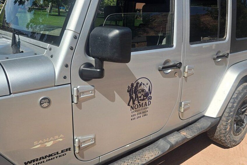 En silverfärgad SUV med logotypen ”Nomad Expeditions” och texten ”Wrangler Unlimited”. 5