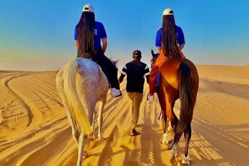 Three people riding horses on a desert trail. 1