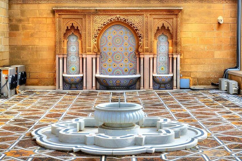 Un cortile con una fontana, archi decorati e piastrelle decorate. 3