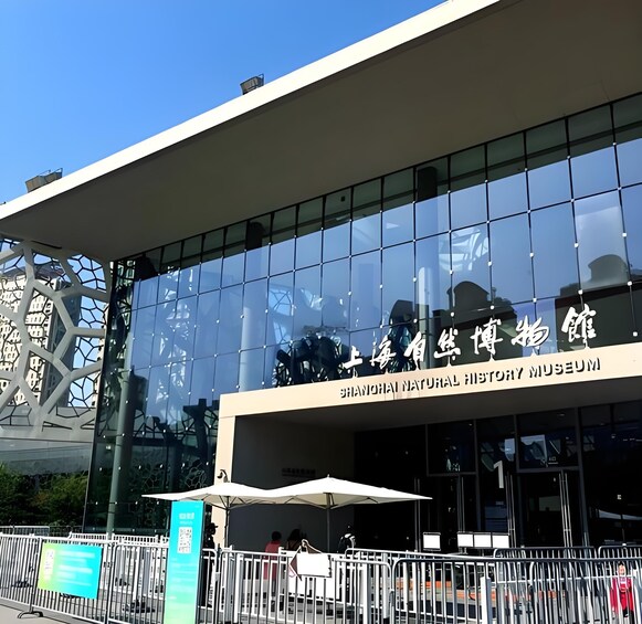 The exterior of the Shanghai Natural History Museum with a modern glass facade and signage in both Chinese and English. 4