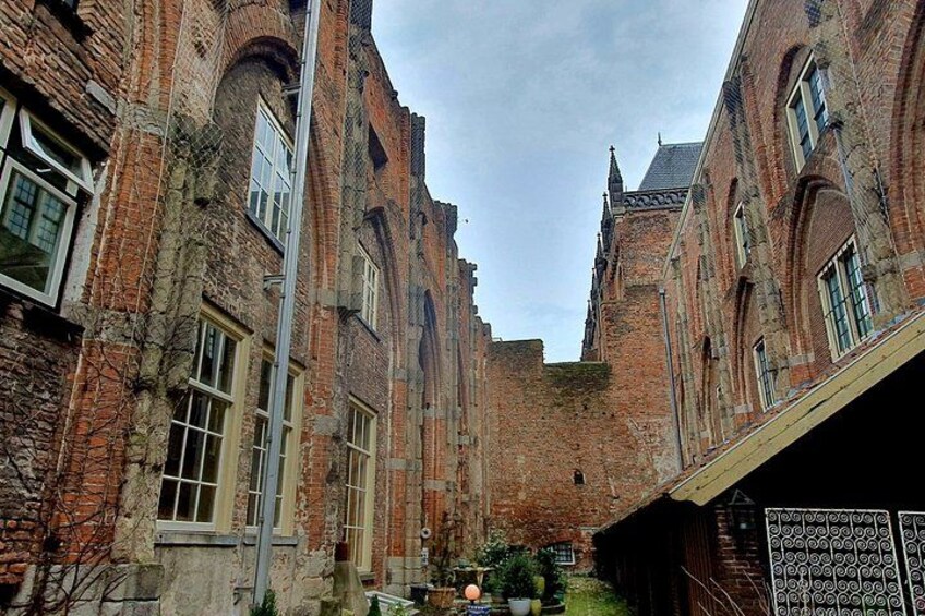A historic brick building with arched windows and a narrow alleyway. 5