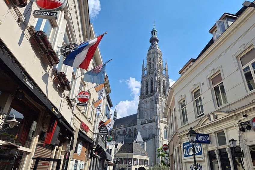 A street with buildings, flags, and a church tower. 4