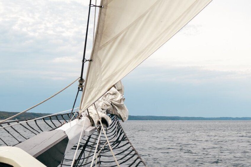 A sailboat with a striped hull and a white sail. 2