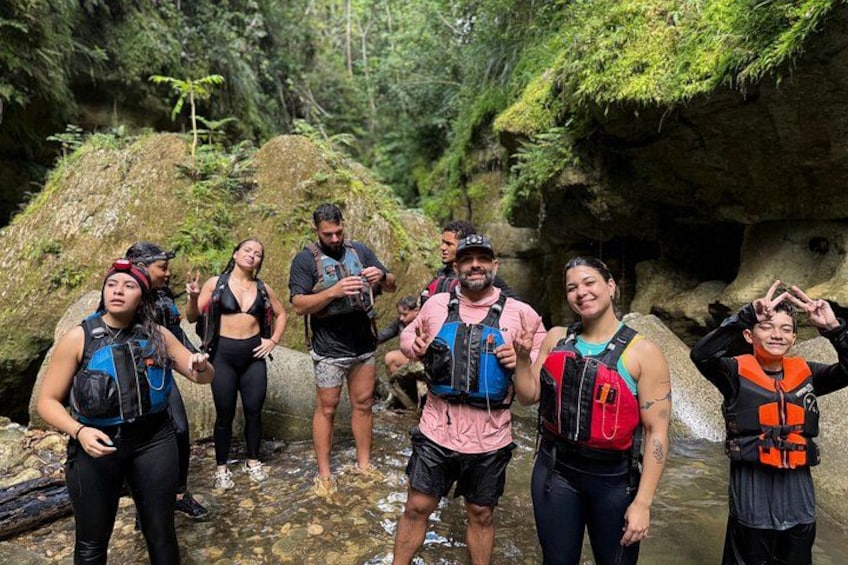 A group of people wearing life jackets and hiking gear in a rocky, forested area. 3