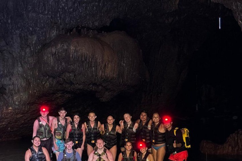 A group of people in a cave with a large rock formation in the background. 5