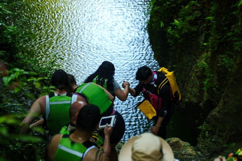 People wearing life jackets and climbing a rocky path near a body of water. 2