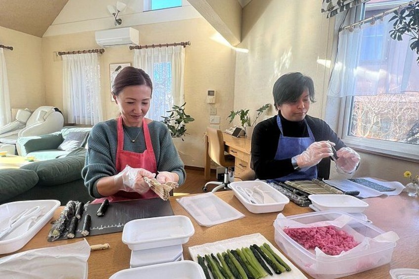 Two people preparing food in a kitchen with various ingredients and utensils on the table. 2