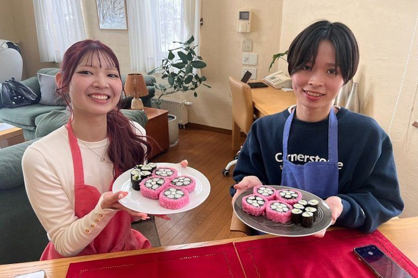 Two individuals holding plates of sushi in a home setting. 4