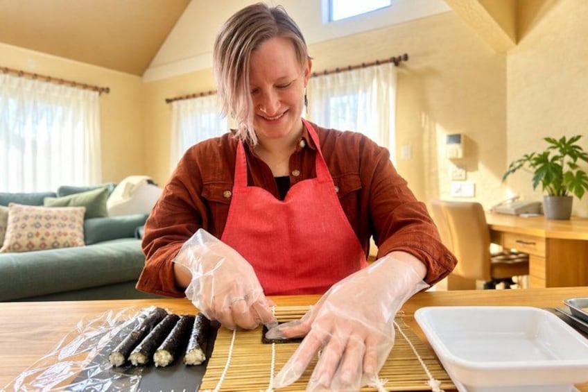 A person in a kitchen wearing an apron and gloves, preparing food. 5