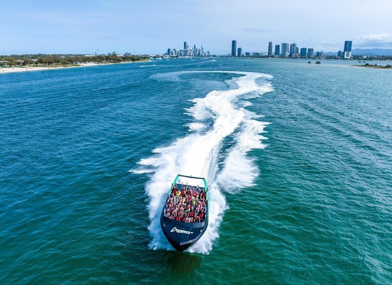 A jet ski with passengers creating a wake in the water, with a city skyline in the background. 1