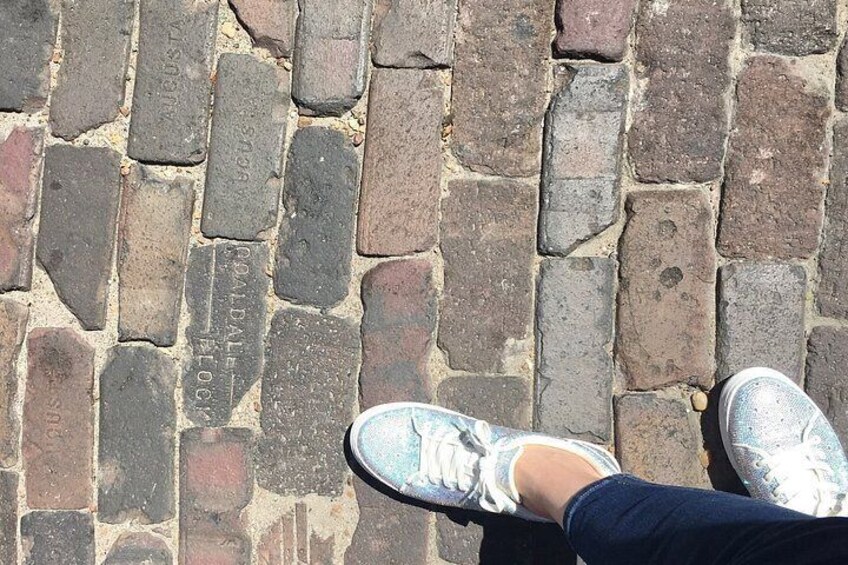 Fødder i hvide sneakers på brostensbelagte fortov. 5