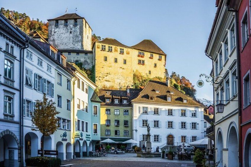 A historic town square with colorful buildings, a prominent tower, and a fountain. 5
