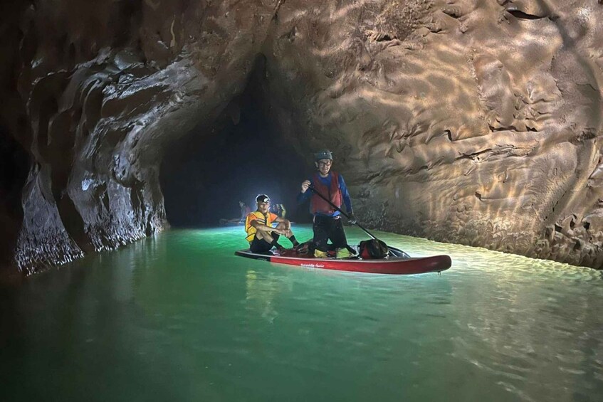 Two people kayaking in a cave with water. 5