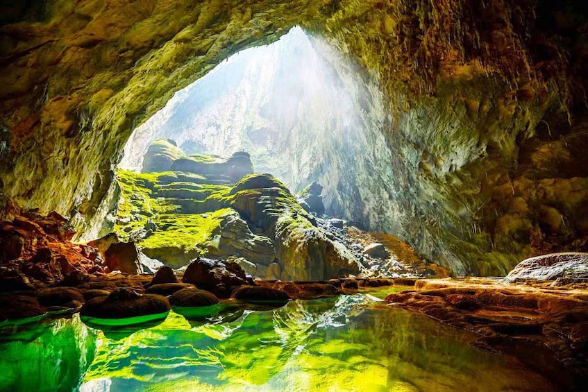 A cave with a water pool reflecting the cave's interior and a natural archway. 5
